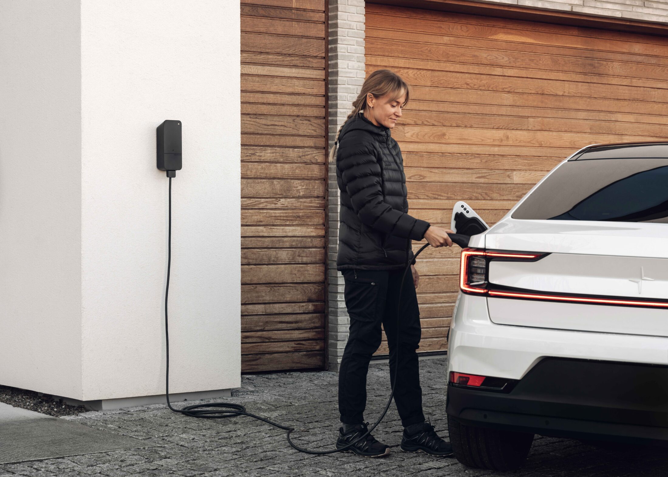 Een elektrische auto wordt naast een betonnen muur opgeladen met behulp van een white-label amina EV-lader met VERDO-branding, waarmee op maat gemaakte oplaadoplossingen voor particulieren worden gedemonstreerd voor energiepartners.