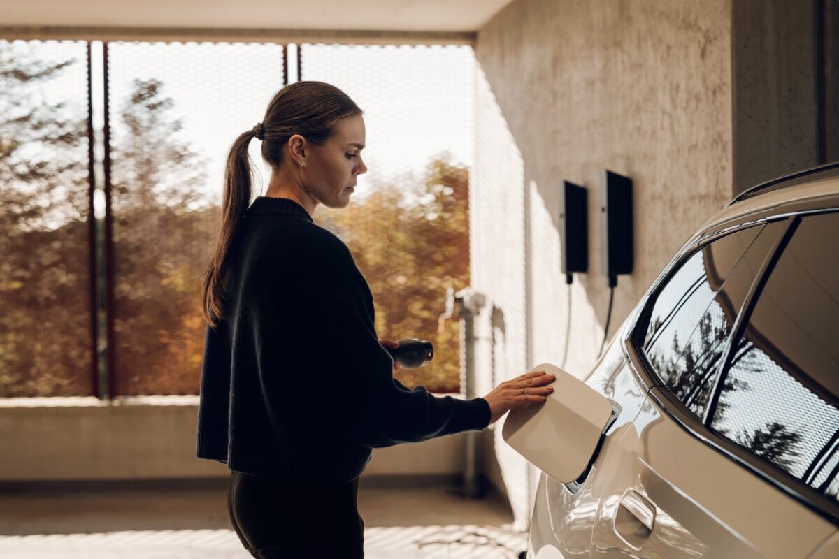 Woman holding charging cable near an EV charging from an amina M