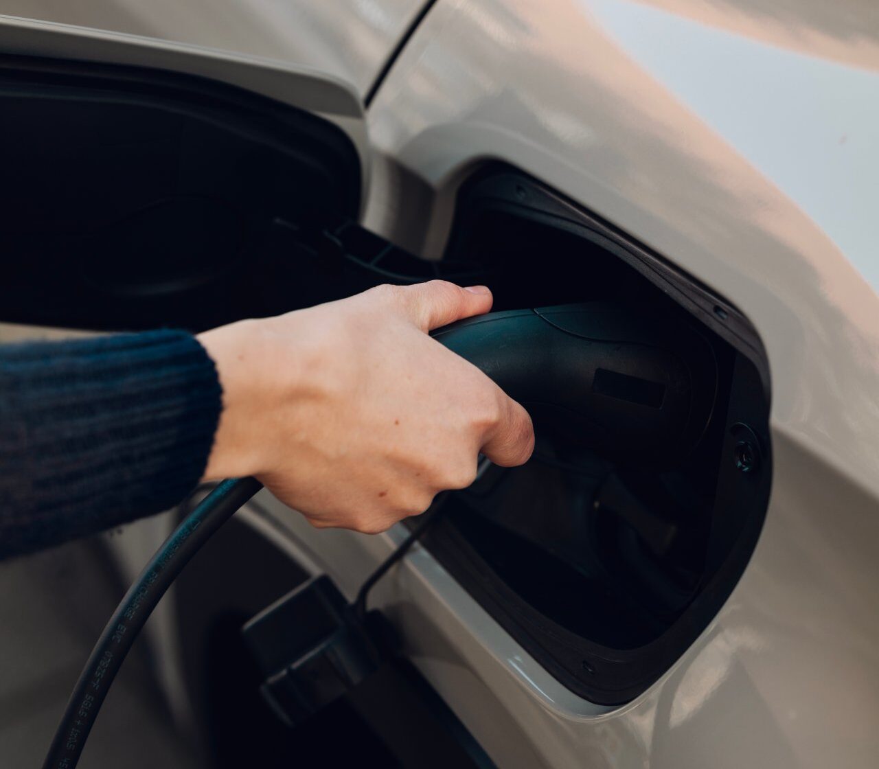 Resident plugging an electric car into an amina EV charging station, showing home charging capabilities