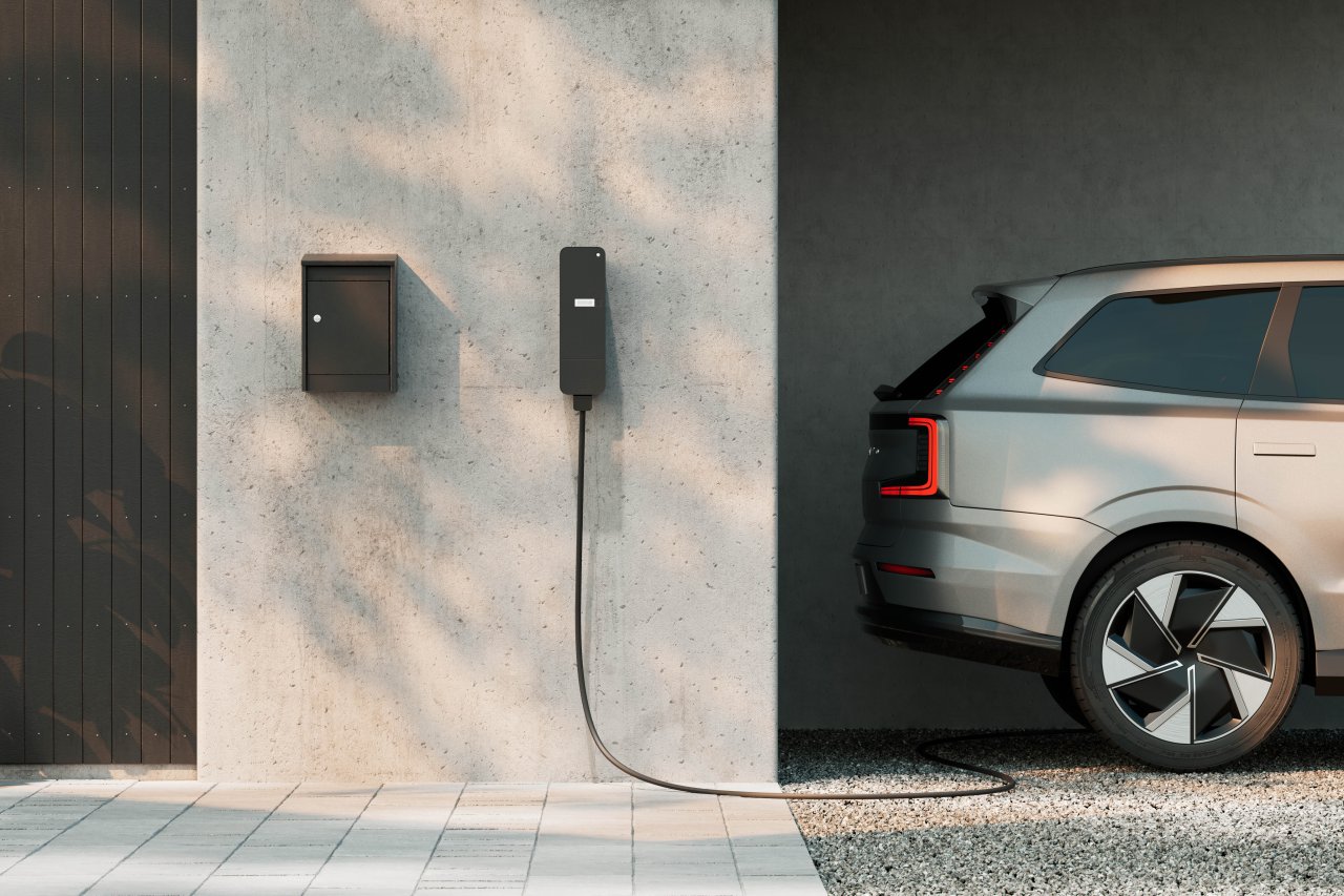 amina wall-mounted EV charger installed on a concrete wall in a residential parking space, charging an electric car in a home setting.